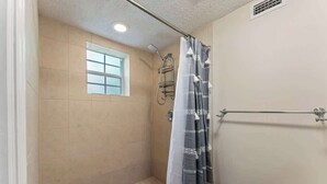 Piccola cabina doccia chiusa, con finestra, soffione e porta asciugamani.