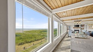 Amplia habitación con grandes ventanales que ofrecen vistas a la playa y las dunas.
