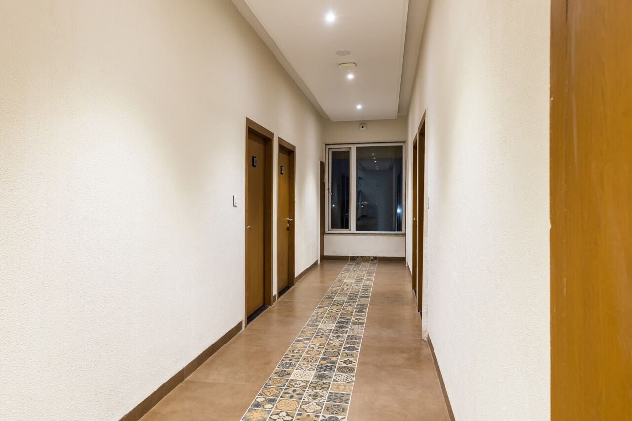 A hallway with tiled flooring, wooden doors, and a large window at the end.