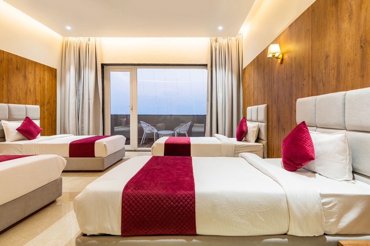 A hotel room with two beds, a balcony, and a view of the city.