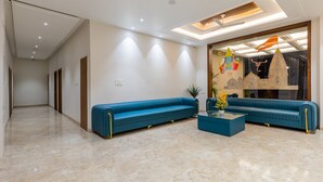 A modern living room with a blue sofa set, a coffee table, and a decorative wall piece. - Gaurison Hotel&Resort (Ujjain)