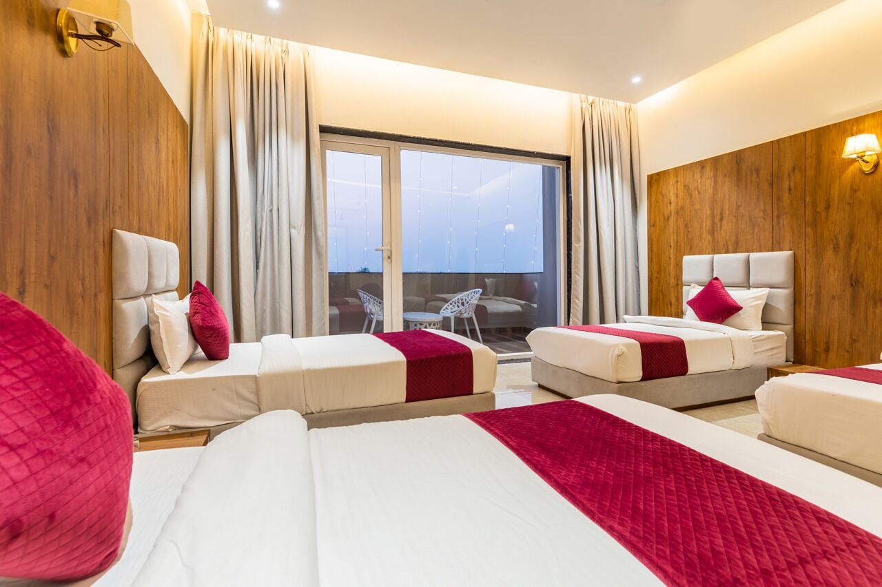 Habitación de hotel con dos camas, un balcón y vistas a la ciudad.