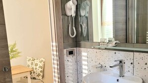 Un baño moderno con un lavamanos grande, un espejo con iluminación y un secador de pelo.