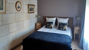 Une chambre à coucher comprenant un lit, deux tables de chevet et deux lampes fixées au mur.