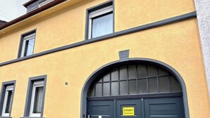 Een geel gebouw met twee garage deuren, een stenen muur en een geparkeerde auto.