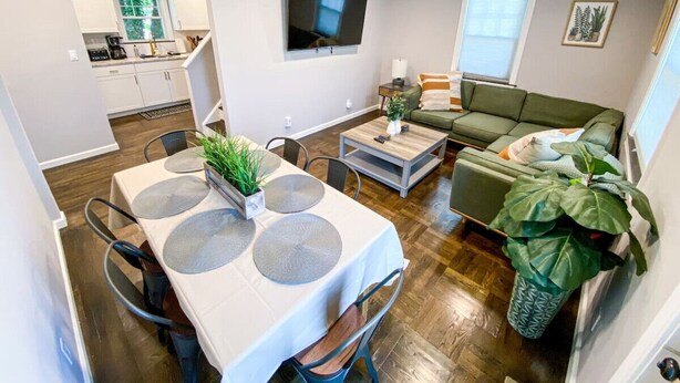 Una sala moderna con comedor, un sofá verde y un televisor montado en la pared.