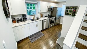 Una cocina moderna con armarios blancos, electrodomésticos de acero inoxidable y piso de madera.