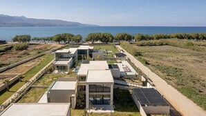 A modern residential complex with multiple detached houses, solar panels, and a view of the sea. - Pnoe Seafront Experience | Villa Alas (Kolymvari)
