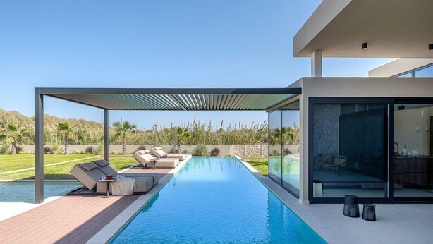 A modern pool area with a clear view of the pool, lounge chairs, and a glass-enclosed structure. - Pnoe Seafront Experience | Villa Etheras (Kolymvari)