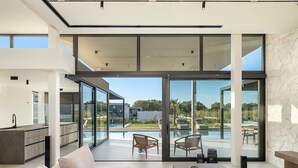 Un'ampia zona giorno con un divano grande, un tavolino da caffè e vista su una piscina esterna e un giardino.