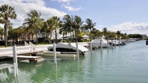 A marina with boats docked, palm trees, and a clear sky. - Beautiful Waterfront Villa 133 Anglers Reef with On-Site Boat Slip  (Islamorada)