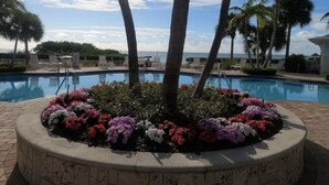 A pool surrounded by a flower bed with palm trees and lounge chairs. - Beautiful Waterfront Villa 133 Anglers Reef with On-Site Boat Slip  (Islamorada)