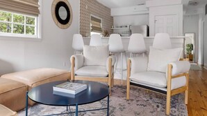 Un salon moderne avec un canapé beige, une table basse ronde et un tapis à motifs.