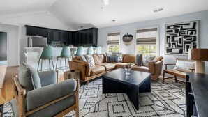 A modern living room with a sectional sofa, a coffee table, and a dining area with a kitchen in the background. - Stylish Getaway in Downtown Charleston (Charleston)