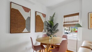 Ein Essbereich mit einem runden Tisch, vier Stühlen und zwei großen abstrakten Bildern an der Wand.
