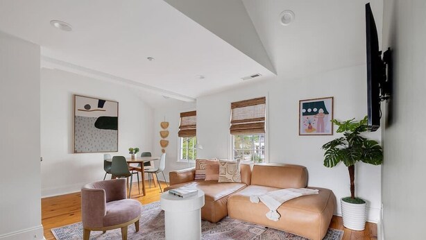 Un salon moderne avec un canapé beige, une table basse ronde et une grande plante en pot.