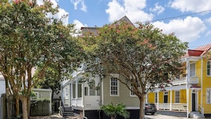 Een tweelaags huis met een veranda, een kleine tuin en uitzicht op de straat.