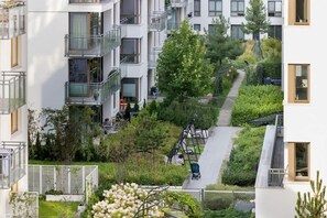 Un immeuble d’appartements moderne doté de balcons, d’un jardin sur le toit et d’un chemin piétonnier.