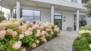 A modern building with a landscaped garden featuring pink hydrangeas. - Stylish Apartment in Wrzeszcz | Balcony | For 4 People (Gdansk)