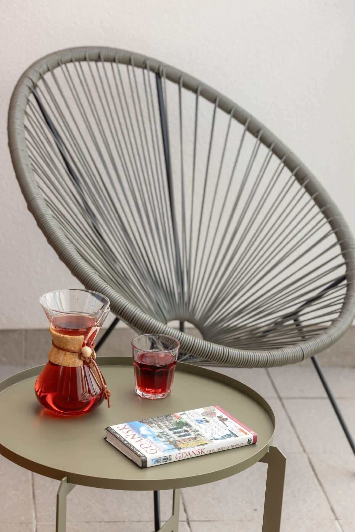 Una mesa redonda con una revista, un vaso de líquido rojo y un juego de té tradicional.