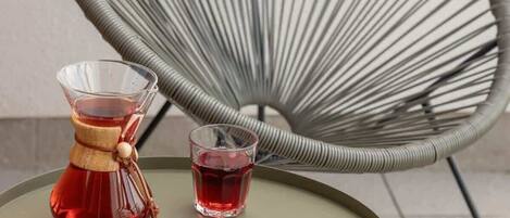 Una mesa redonda con una revista, un vaso de líquido rojo y un juego de té tradicional.