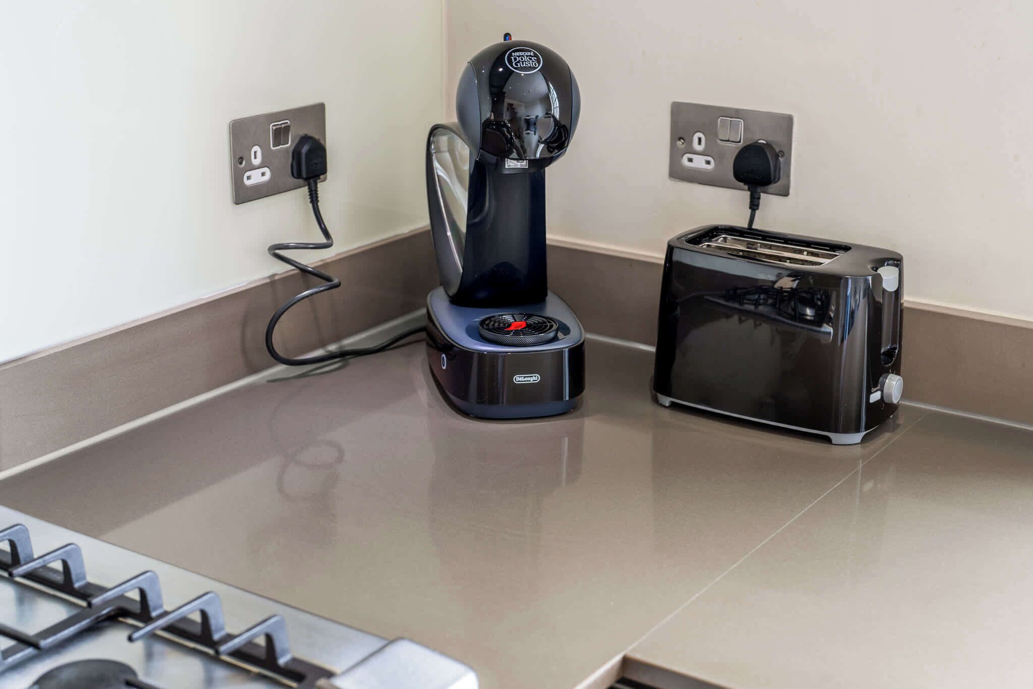A kitchen with a coffee machine, toaster, and stove.