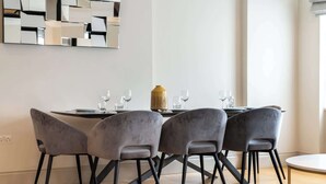 A modern dining area with a round table, four grey chairs, and a decorative vase.