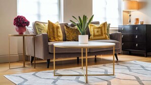 A modern living room with a sofa, a round coffee table, a side table with a vase, and a lamp.