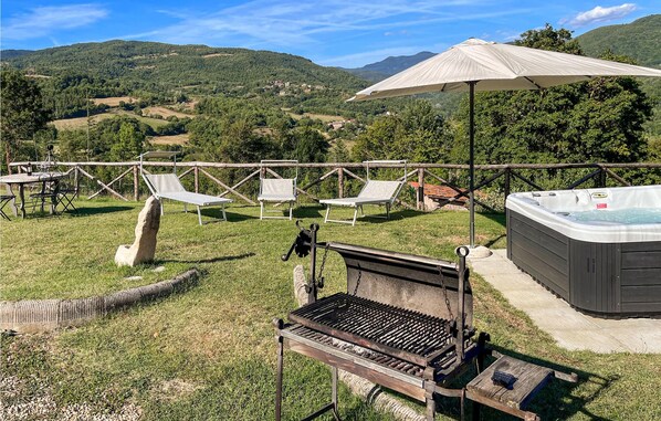 Ein Garten mit Grill, Liegestühlen, einem Whirlpool und Blick ins Grüne.