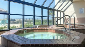 Un espace avec un bain à remous doté d’un toit en verre, une piscine et une vue sur l’extérieur.