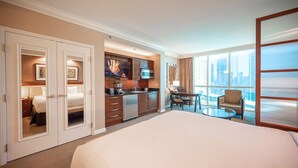 Une chambre d’hôtel dotée d’un grand lit, d’une kitchenette, d’un coin repas et offrant une vue sur la ville.