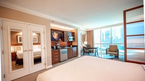 Una habitación de hotel con una cama grande, kitchenette, comedor y vistas de la ciudad.