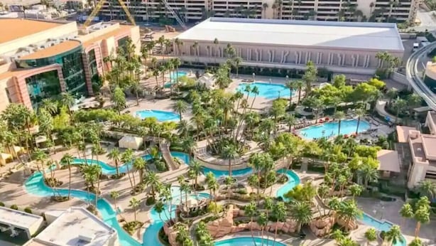Un resort con varias piscinas rodeado de palmeras y zonas de descanso.