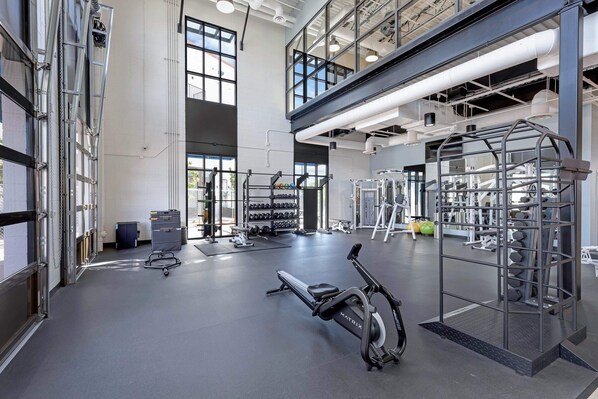 A spacious gym with various exercise equipment, including a treadmill, weight machines, and a squat rack.