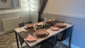 A dining table set with pink napkins, plates, and wine glasses, with a mirror and a spiral light fixture on the wall. - Stunning spacious one bedroom apartment in courtyard location, central to town (Belper)