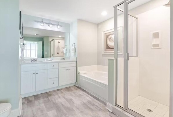 A modern bathroom with a walk-in shower, a double vanity with a large mirror, and a bathtub.