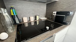 A Samsung chef collection induction cooktop with four stainless steel containers on a marble countertop.