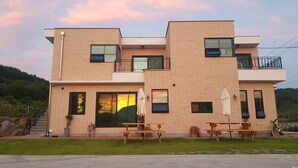 Un edificio moderno de dos pisos con fachada de ladrillo, ventanas grandes y un balcón.