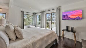 A modern bedroom with a large bed, a desk, and a painting of a mountain landscape. - Luxury Mountain retreat with Hot tub (Zephyr Cove)