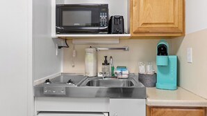 A compact kitchen with a microwave, coffee maker, and a coffee machine on the countertop. - Cozy Lazy Duck Inn #15 features a King bed and kitchenette, just 1 min from Yellowstone. (West Yellowstone)