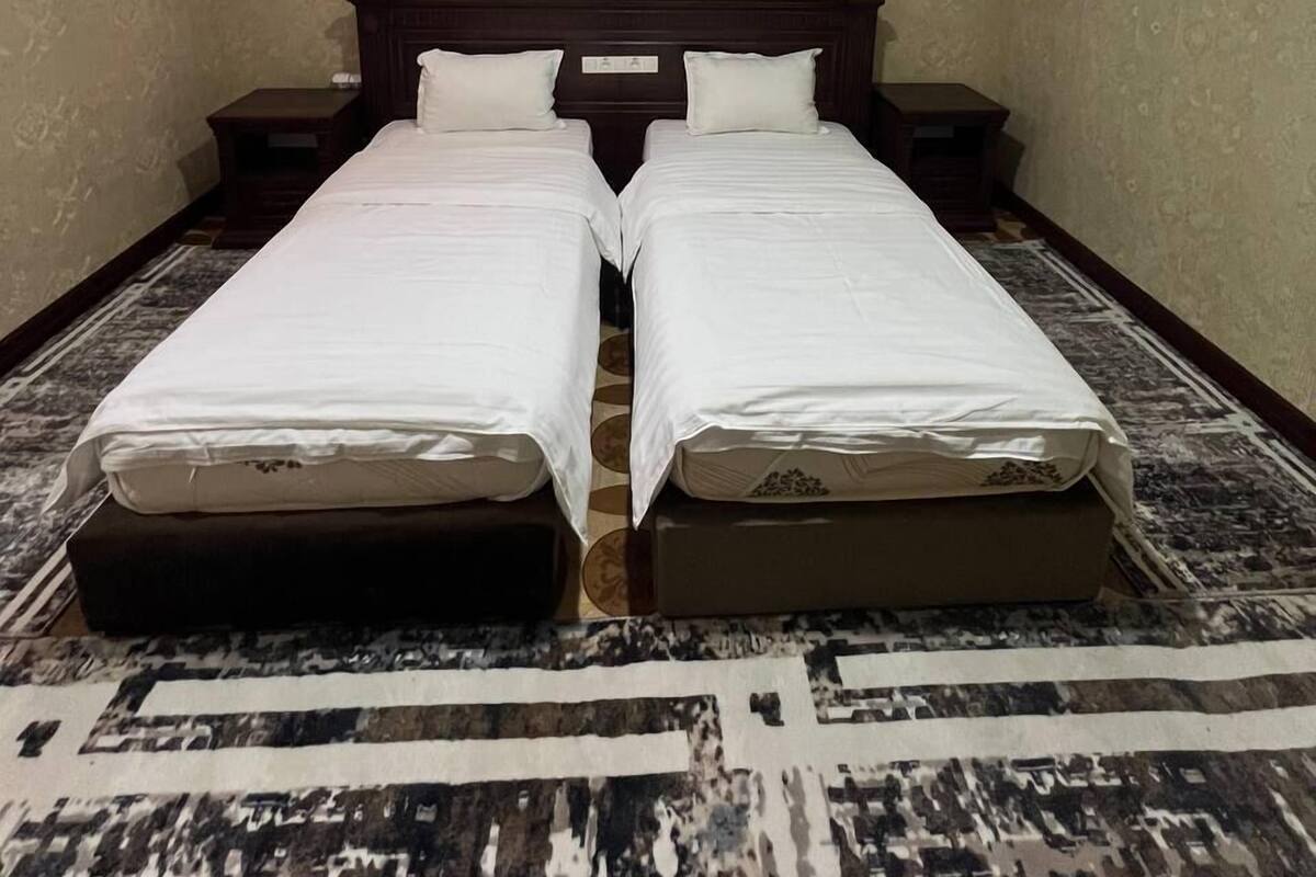 A room with two beds, a skylight, a headboard, and a patterned rug.