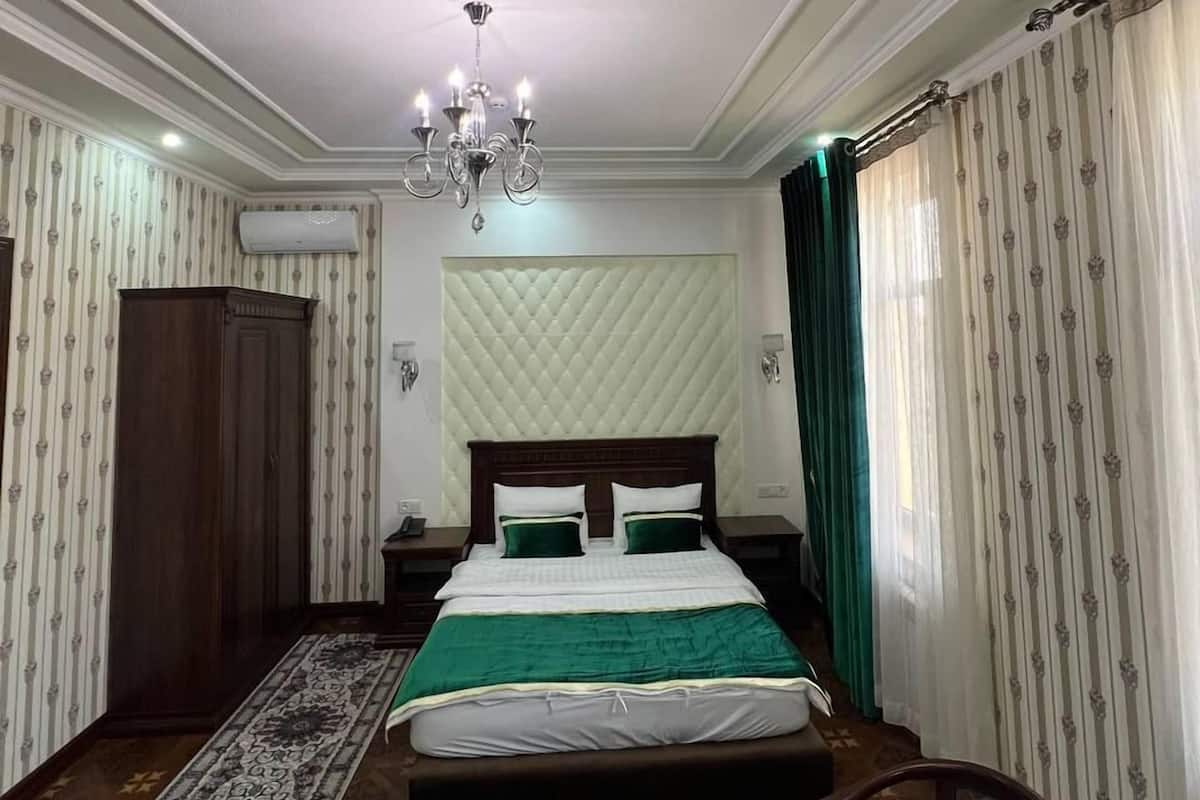 A hotel room with a bed, a chandelier, a round table, and a wardrobe.