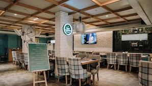 Un restaurante con pared de ladrillo, techo de madera y sillas a cuadros.