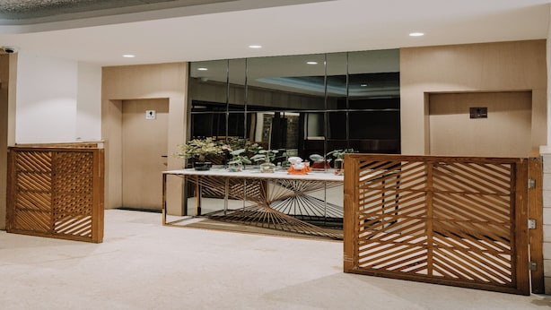 Un interior moderno con un separador de vidrio, una mesa con plantas en macetas y un separador de madera con un diseño geométrico.