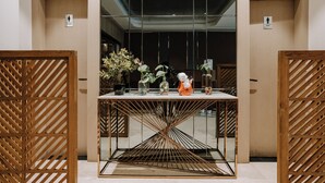 Un interior moderno con una mesa central, separadores de madera y plantas en macetas.