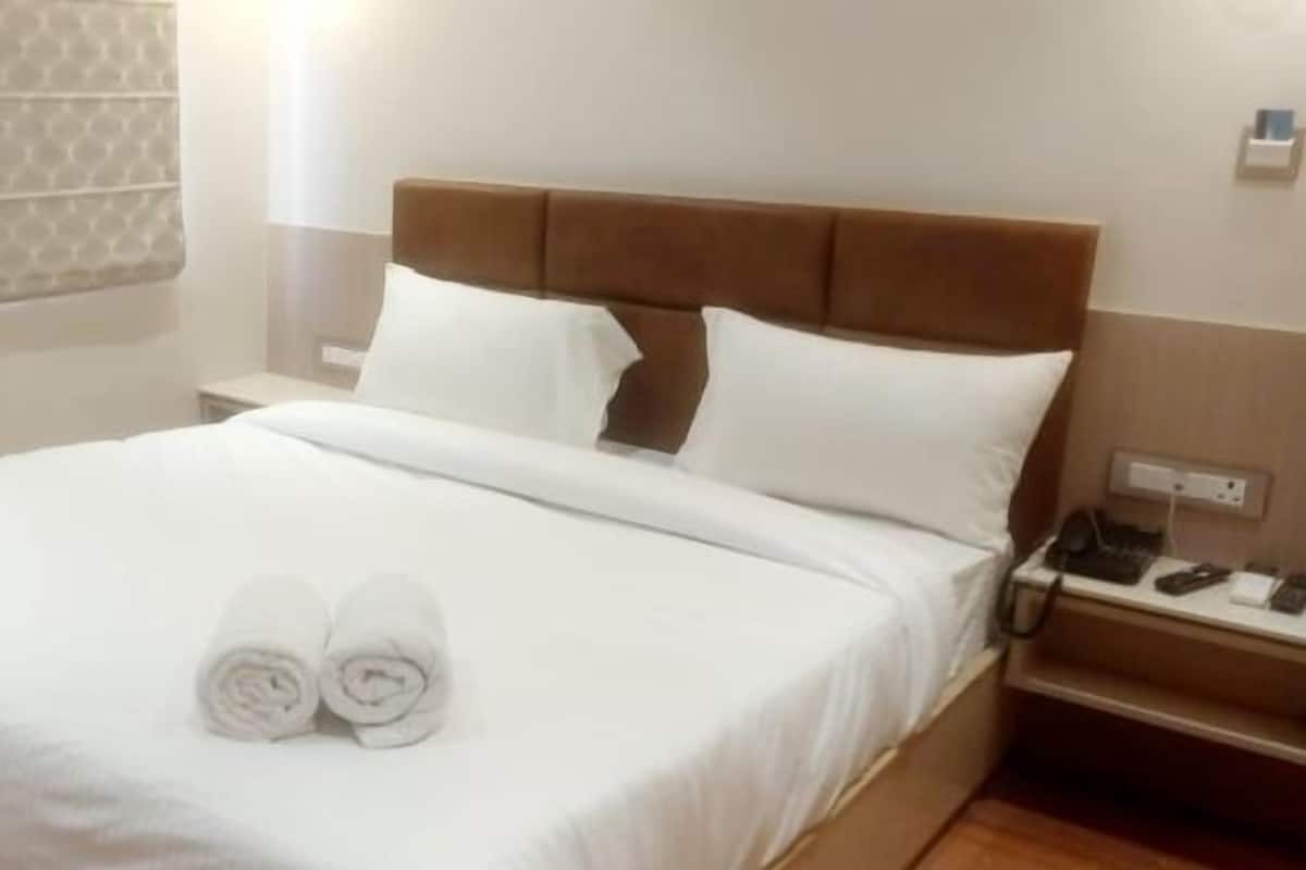 Un lit bien fait, avec des draps blancs et deux serviettes enroulées posées dessus.