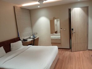 Een hotelkamer met een groot bed, een nachtkastje met een lamp, een garderobe en een spiegel.