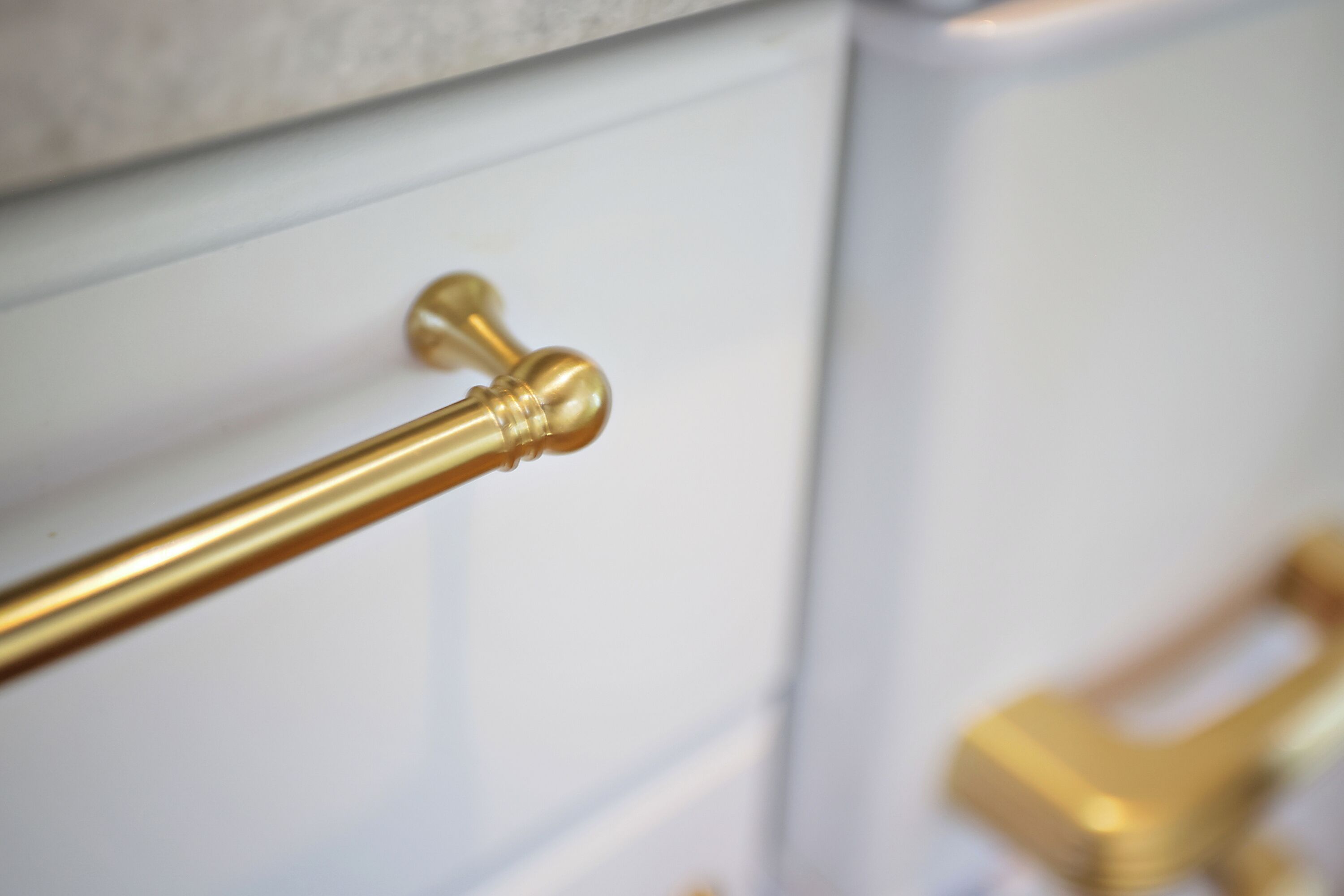 A close-up of a brass towel rack on a white tiled wall.