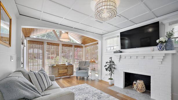 A modern living room with a fireplace, a large TV, and a cozy seating area.