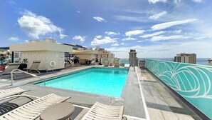 Ein Poolbereich auf dem Dach mit Liegestühlen und Blick auf den Ozean.